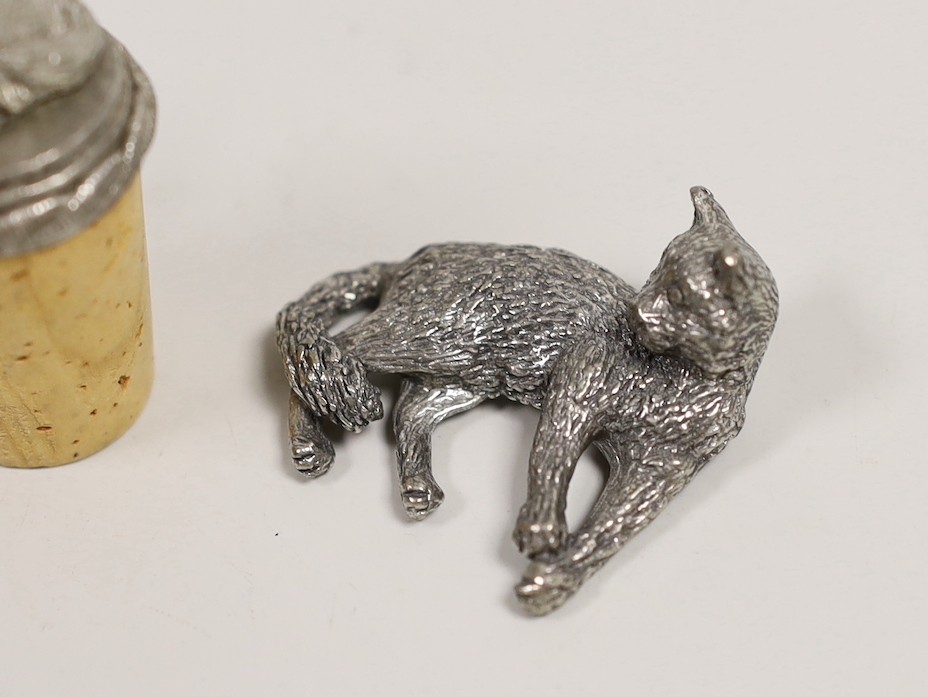A modern silver miniature free standing model of a cat, with raised paw, London, 1995, length 37mm, together with four other base metal cats and a mouse and a cork stopper with cat finial.